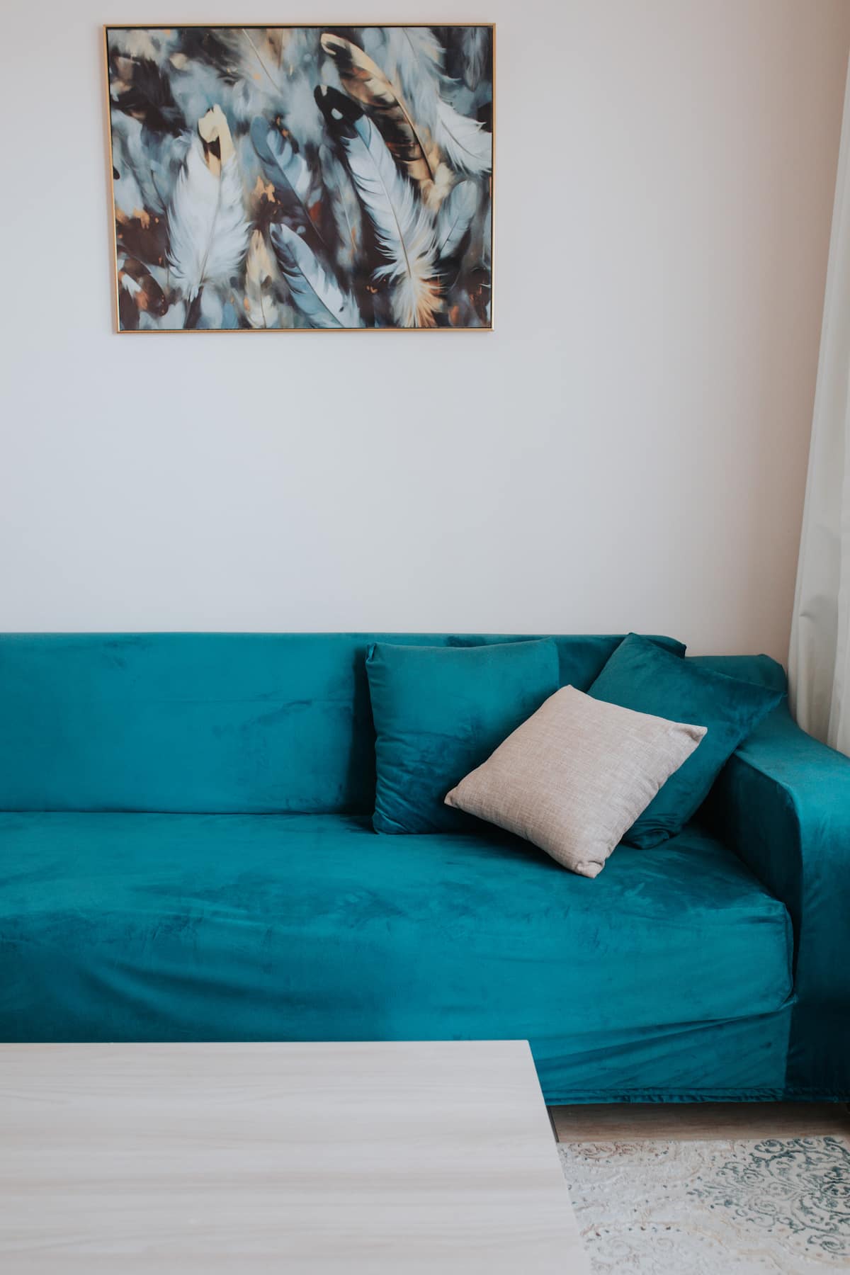 Wohnzimmer mit Petrol-Sofa und Federbild